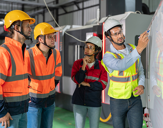 Journey of sustainability and innovation. A pivotal moment in an industrial plant. Knowledgeable supervisor takes center stage in front of a whiteboard, passionately explaining comprehensive plans to a diverse group of engaged engineer employees.